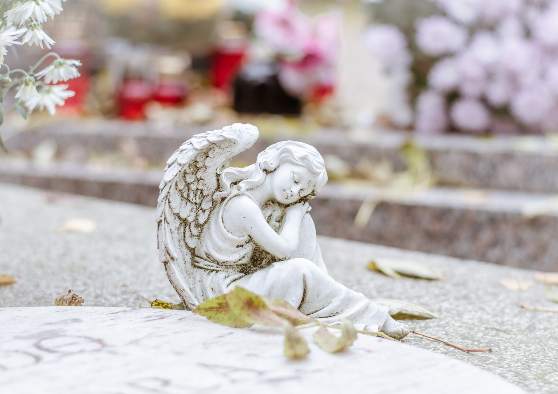 Figura de un ángel alado a los pies de una lápida en el cementerio