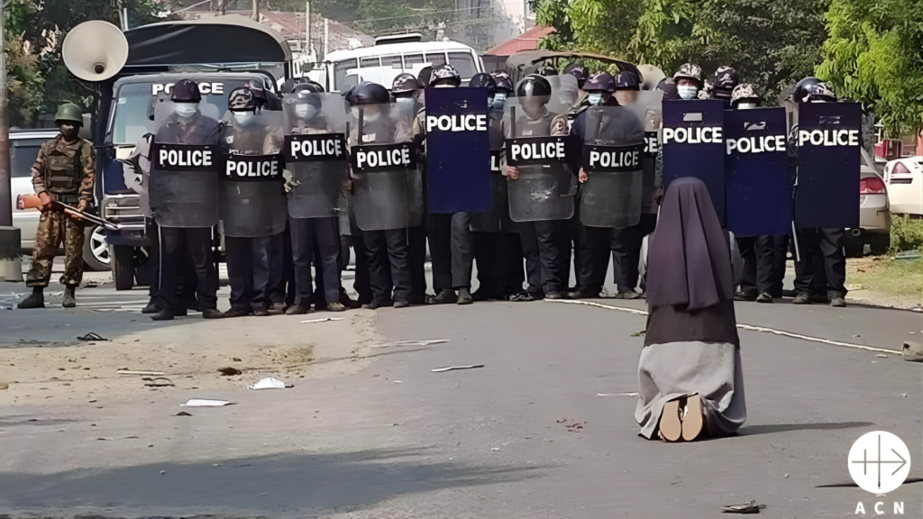 Una religiosa reza delante de una fila de policías con escudo